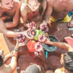 Happy friends having fun cheering with wine in boat party - Young people enjoying summer vacation together toasting sangria an eating watermelon - Youth and friendship concept - Focus on glasses